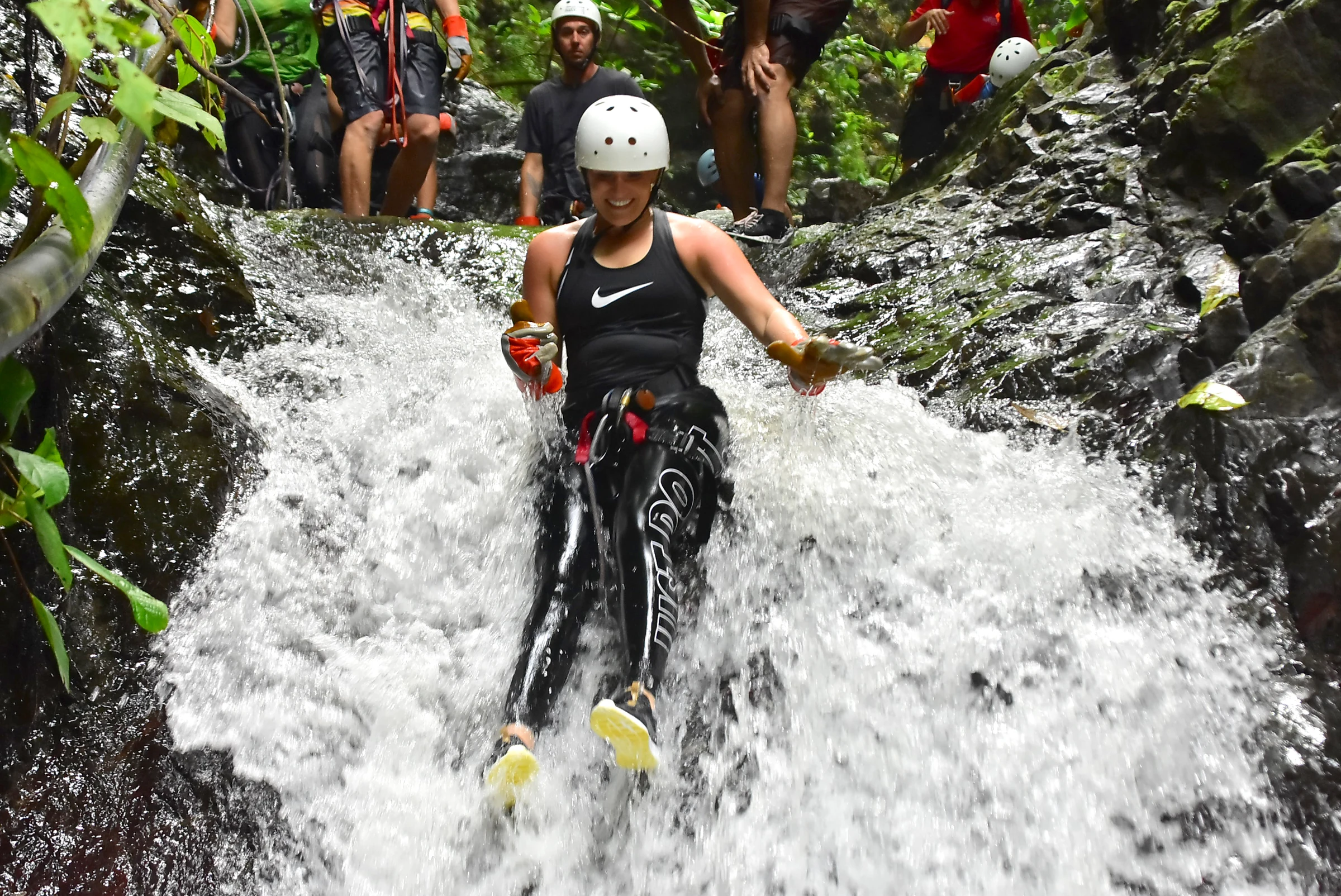 A guest rappelling down a rushing waterfall