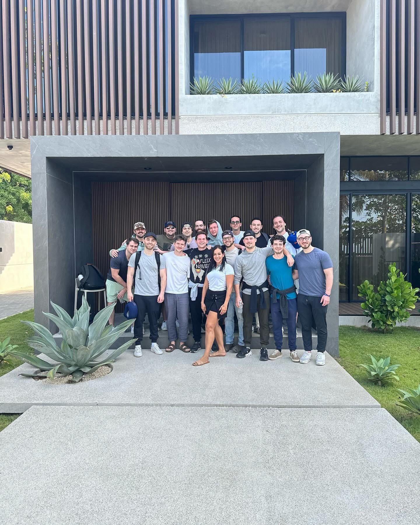 A large group of guests posing at the entrance of a modern villa