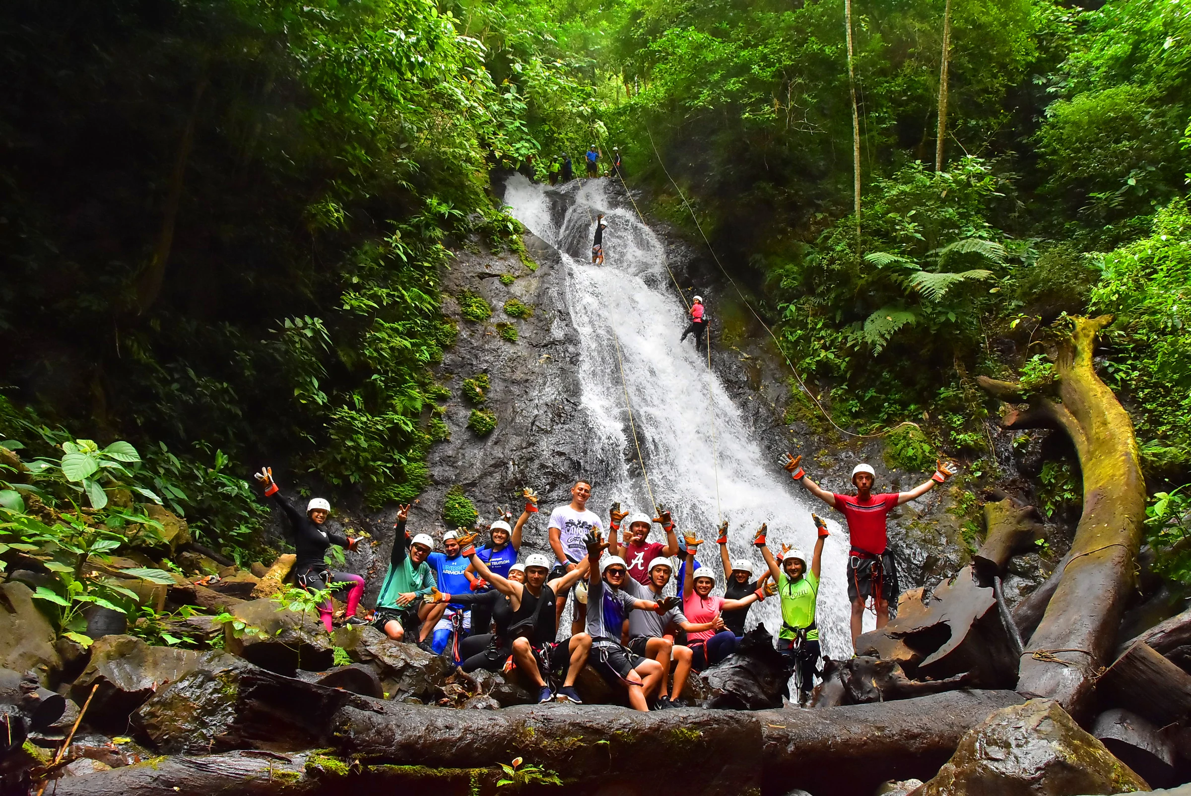A canyoning group gathered beneath a waterfall