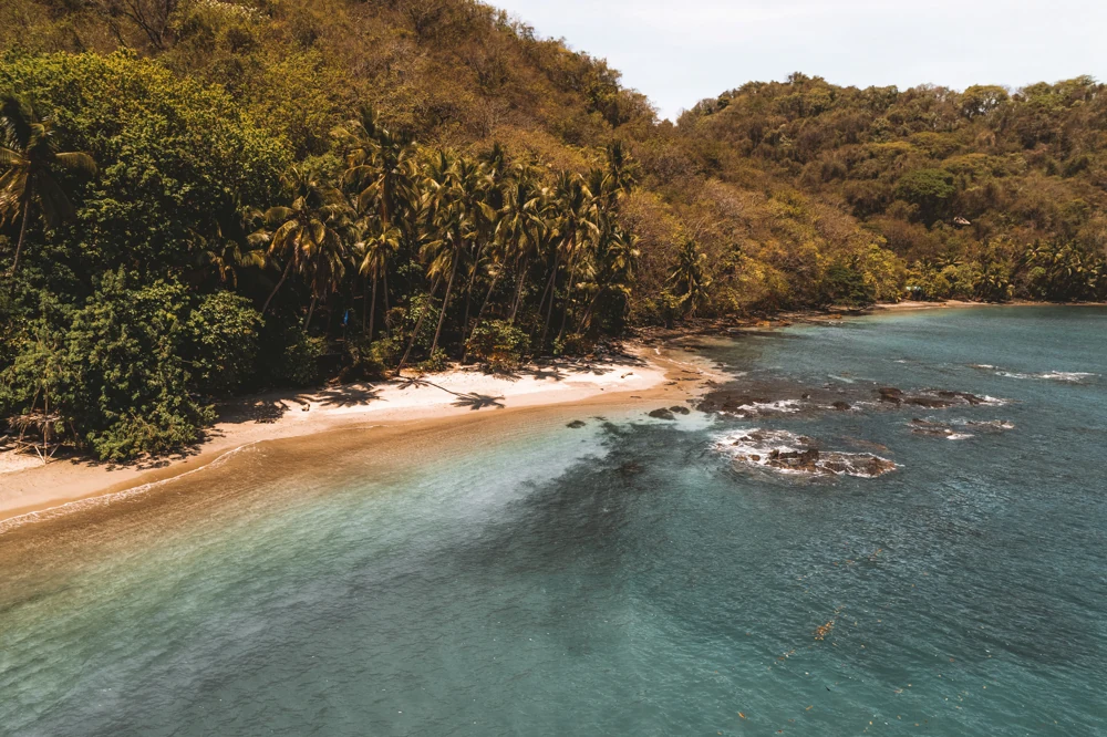 A golden beach and turquoise bay from above