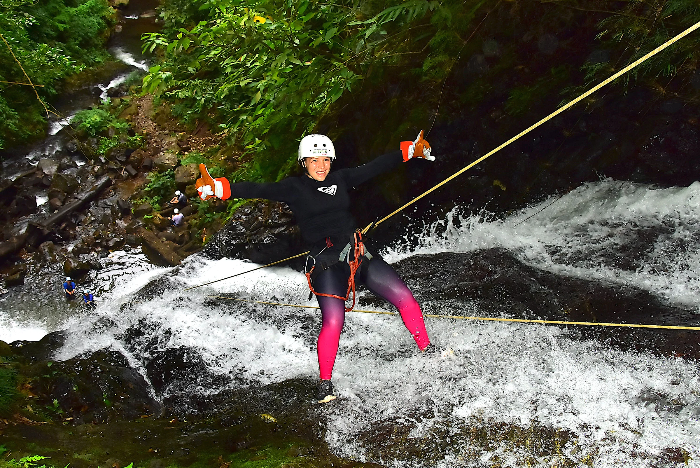 A canyoner descending beside a waterfall on a rope