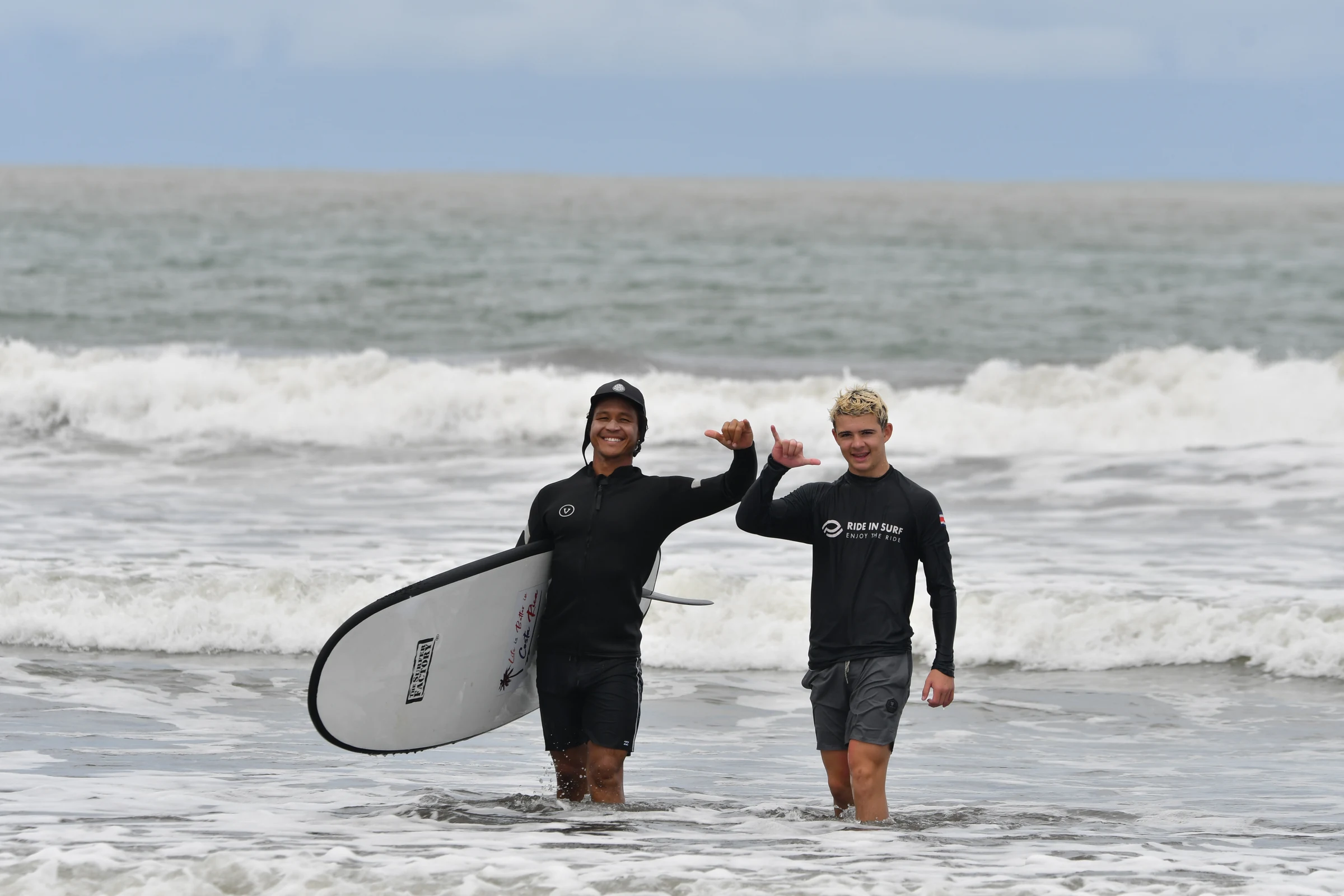 A surf coach and student walking out with a board