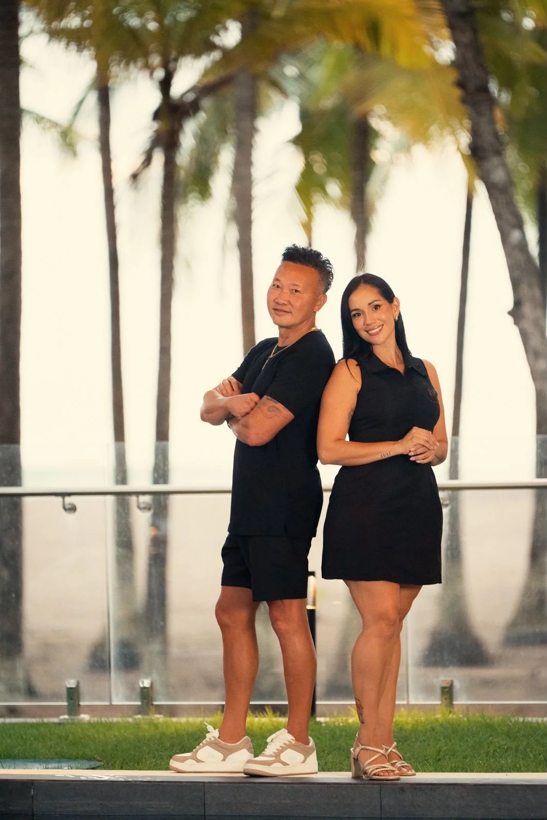Two Luxe Voyage planners standing back to back among the palms at golden hour