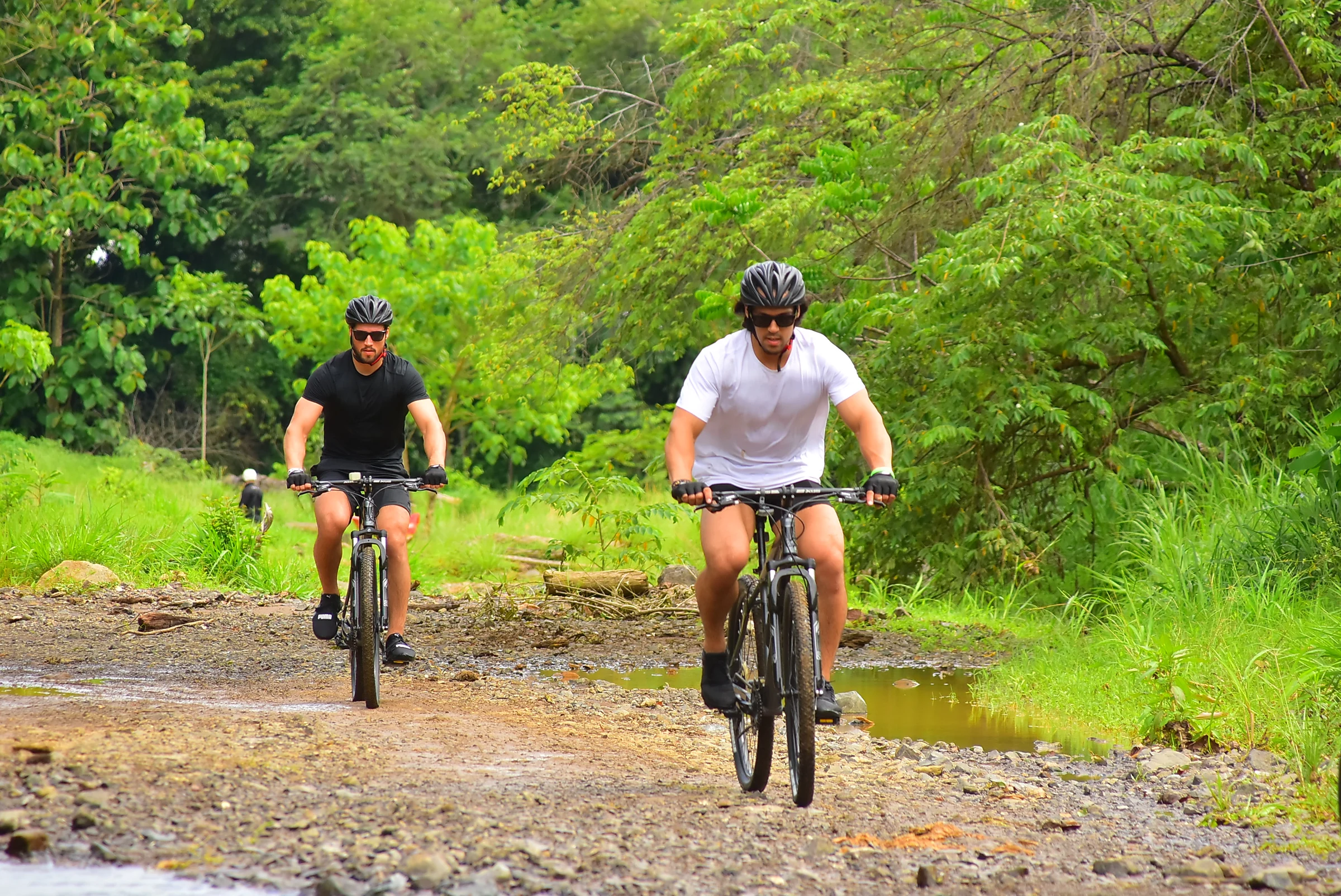 Mountain bikers riding through a jungle creek