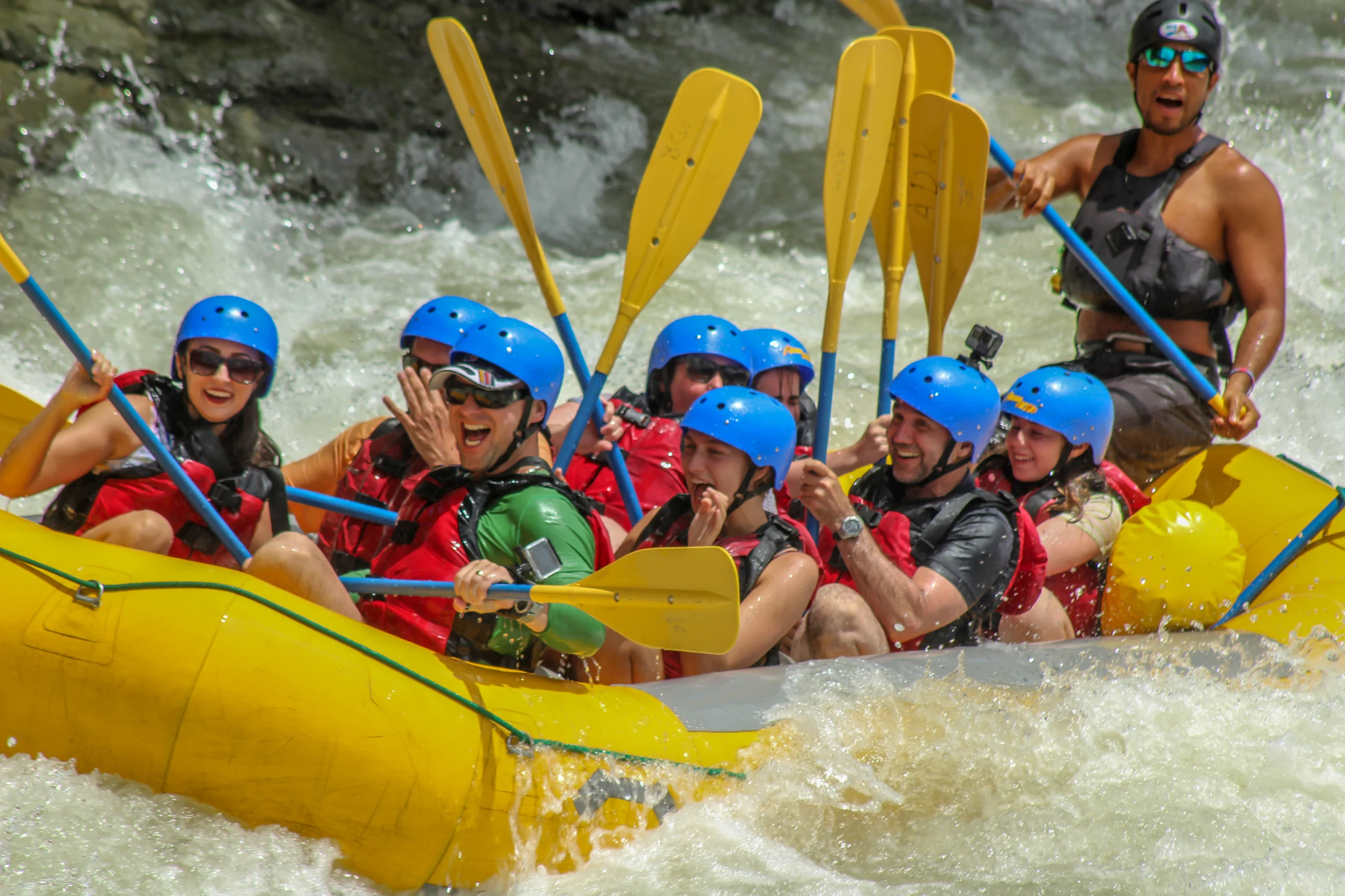 Guests paddling a yellow raft through white water