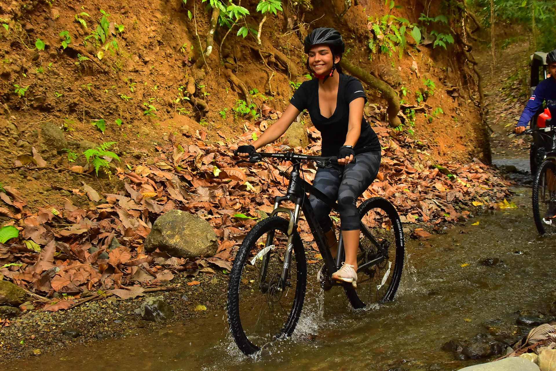A guest riding a mountain bike through a shallow jungle creek