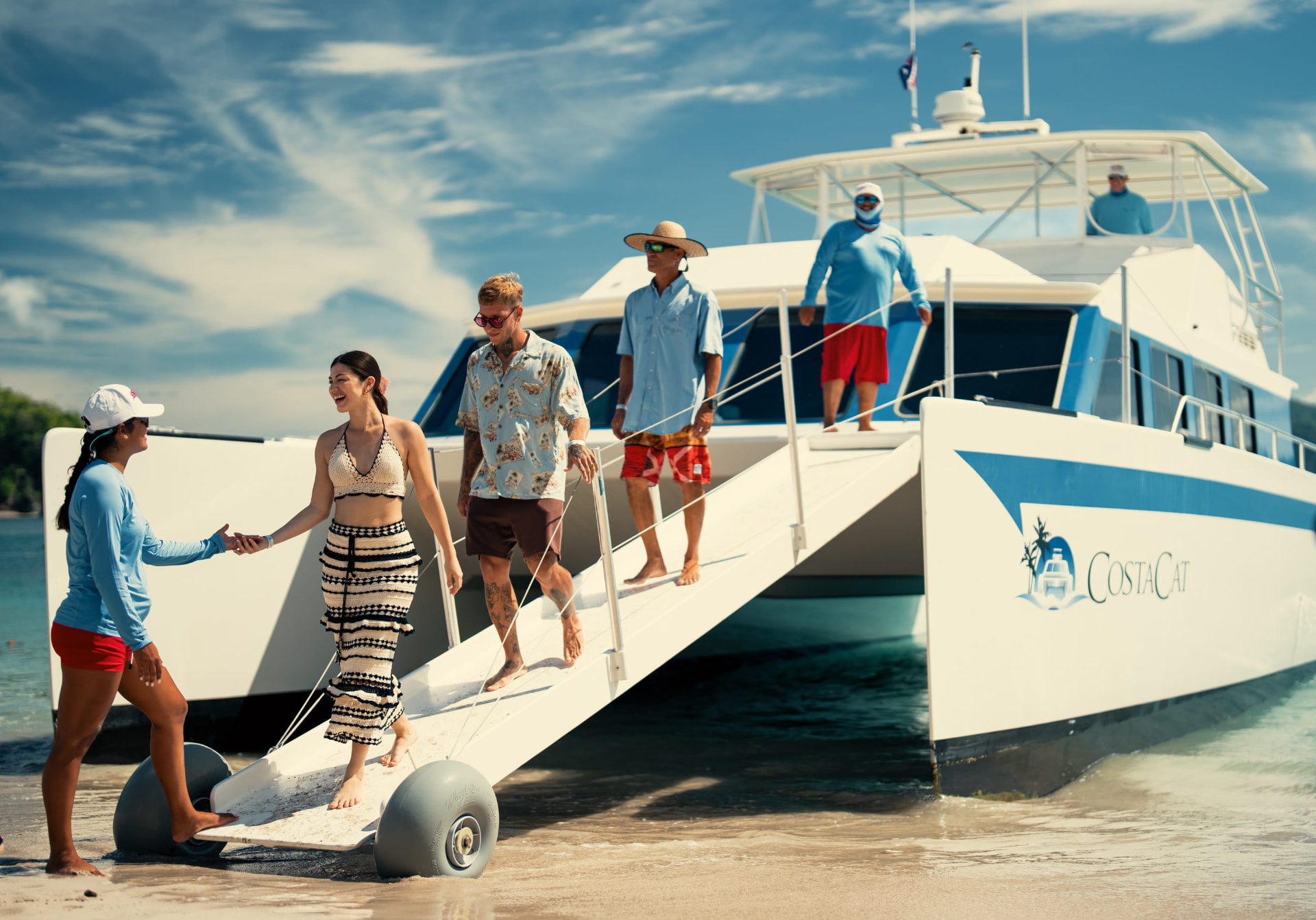 Guests walking down a catamaran gangway onto a quiet Costa Rican beach