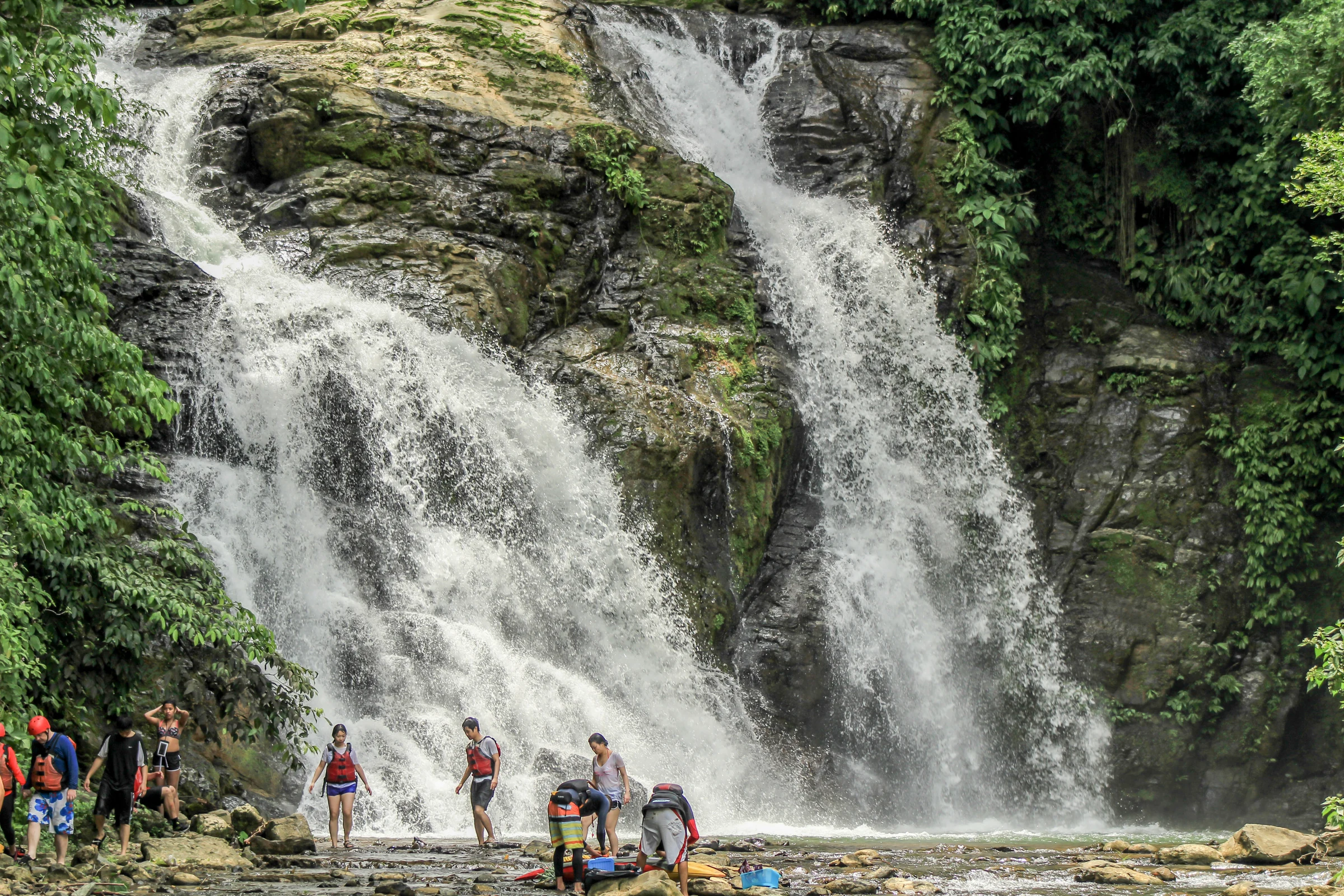 A tall waterfall above the river on a rafting day