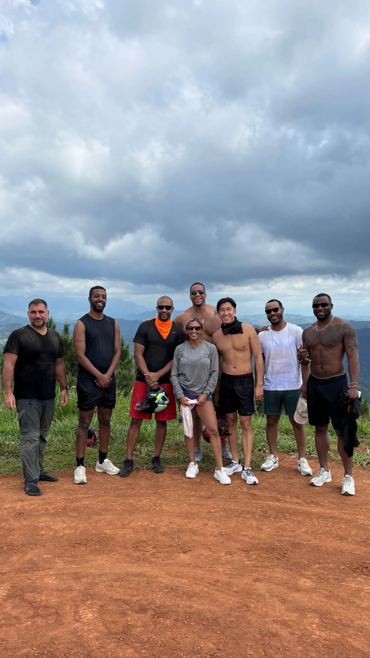 A group of friends standing on a hilltop road above the coast