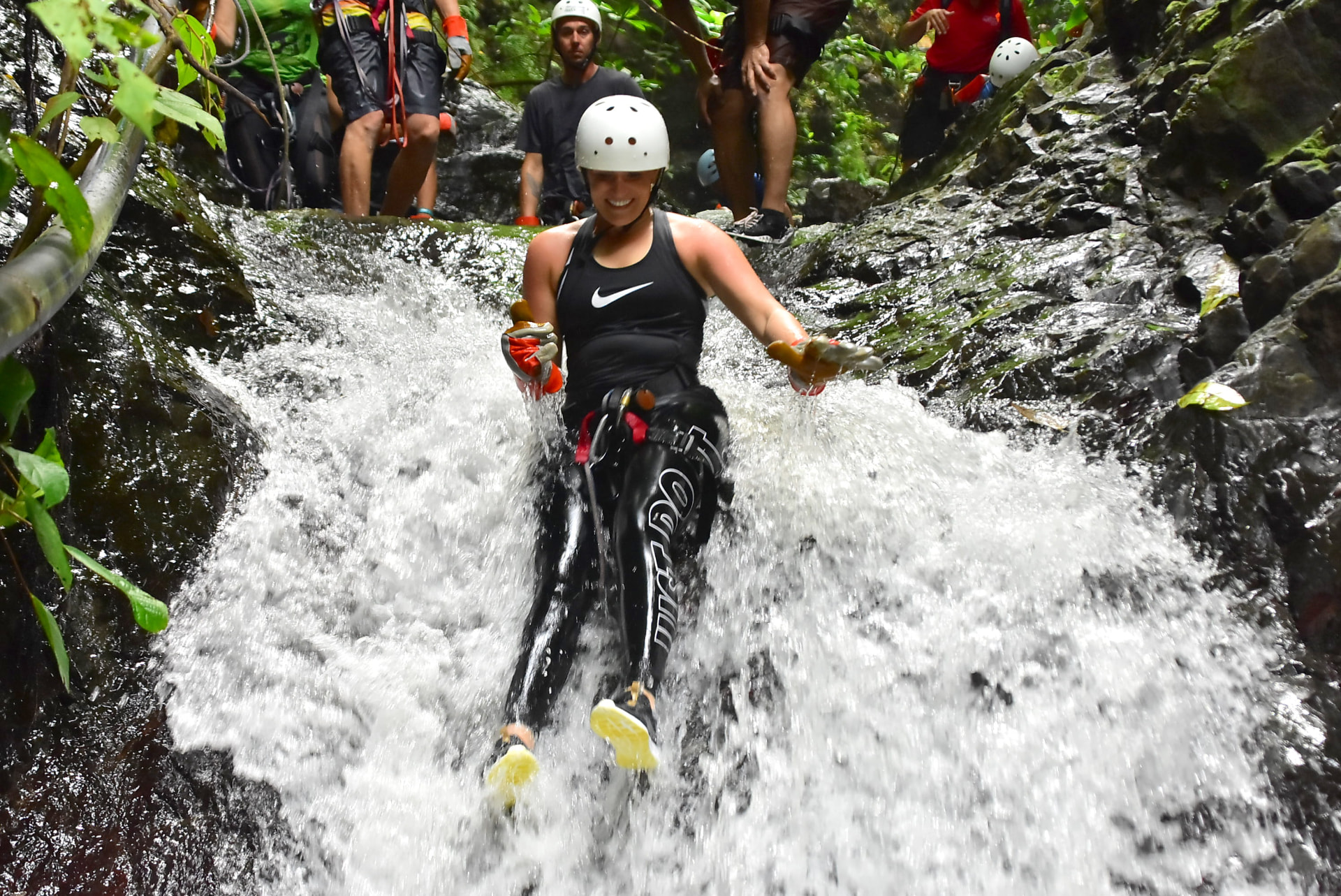 A guest sliding down a natural waterfall chute during a canyoning tour